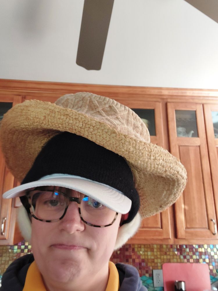 Person wearing multiple hats on top of each other with an annoyed expression