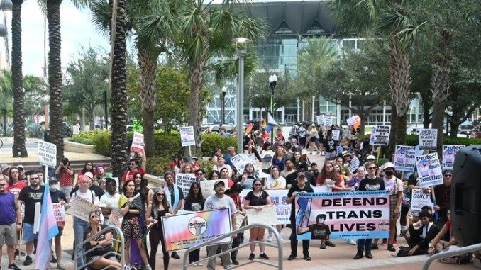 Trans rights protesters holding signs and banners outside Orlando City Hall on October 7, 2023