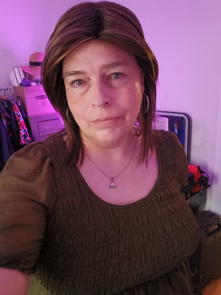 Melinda, a white woman with medium brown hair, wearing a green peasant blouse.