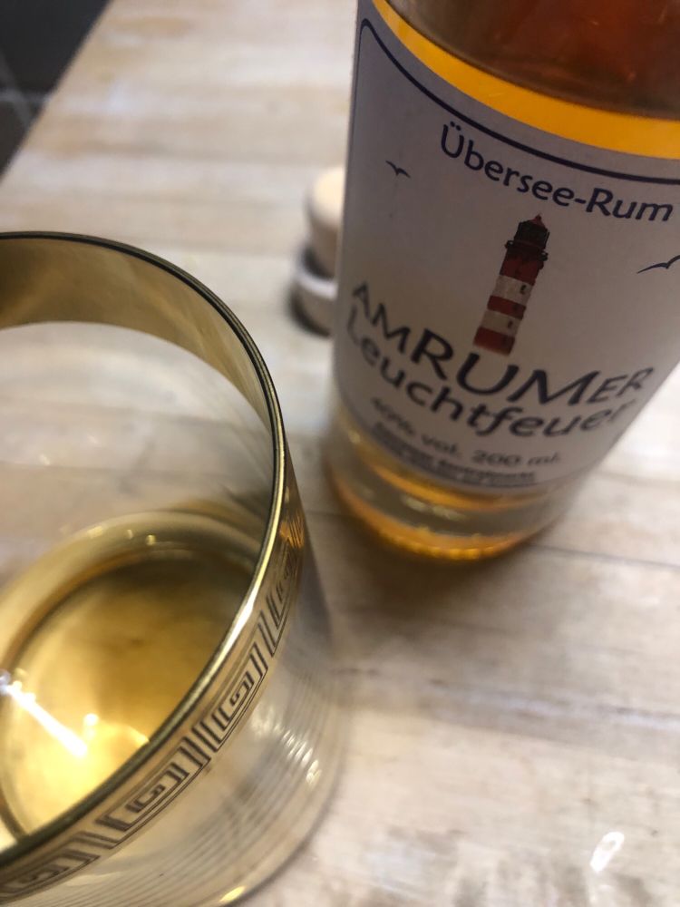 Schönes Glas mit Goldrand und Amrum daneben in der schiefen Flasche