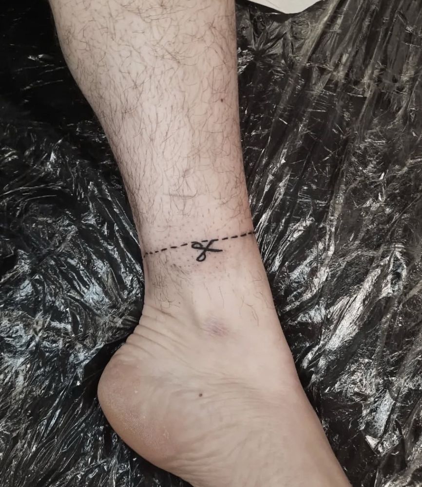 photo of a tattoo of a “cut here” guideline around a lower leg