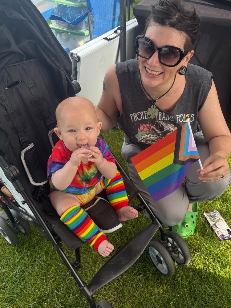 Chloe and her kid wearing rainbow and holding a pride flag 