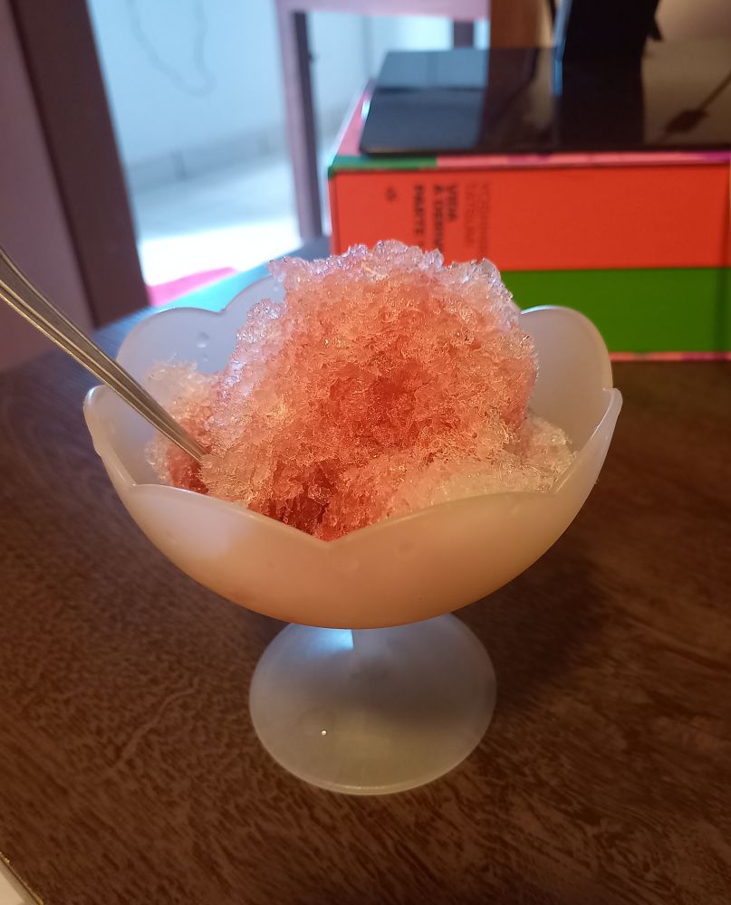 Tacinha de plástico branca contendo raspadinha de gelo coberta de groselha