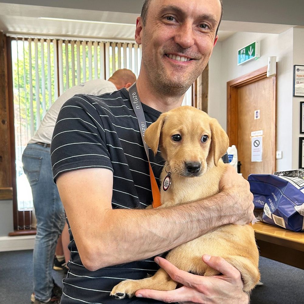A man holding a small, gold-coloured puppy