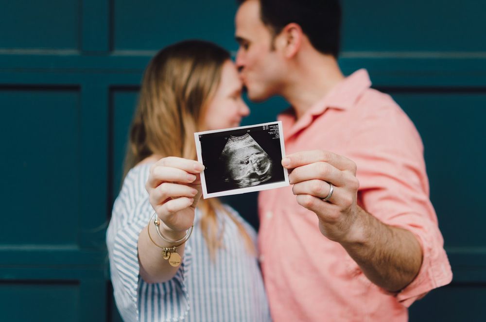 A happy couple proudly displays their ultrasound photo, symbolizing their excitement for the new baby on the way