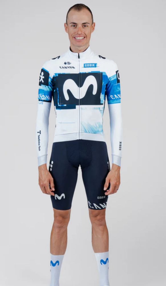 Enric Mas poses in the new Movistar kit. The jersey is white with a navy panel on the chest displaying the white Movistar M, and the light blue around the panel extends to the top of the sleeves. 