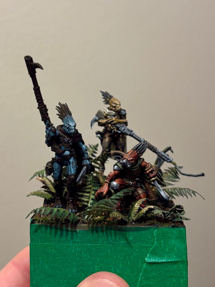 A miniature vignette of three "kroot" aliens exploring a forest