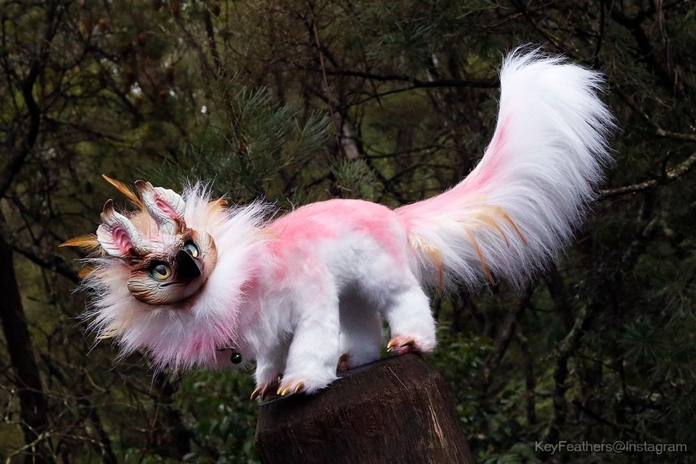 Fluffy white and pink griffin art doll. With a long fluffy tail, sculpted face and golden claws, and a large mane of fluffy fur