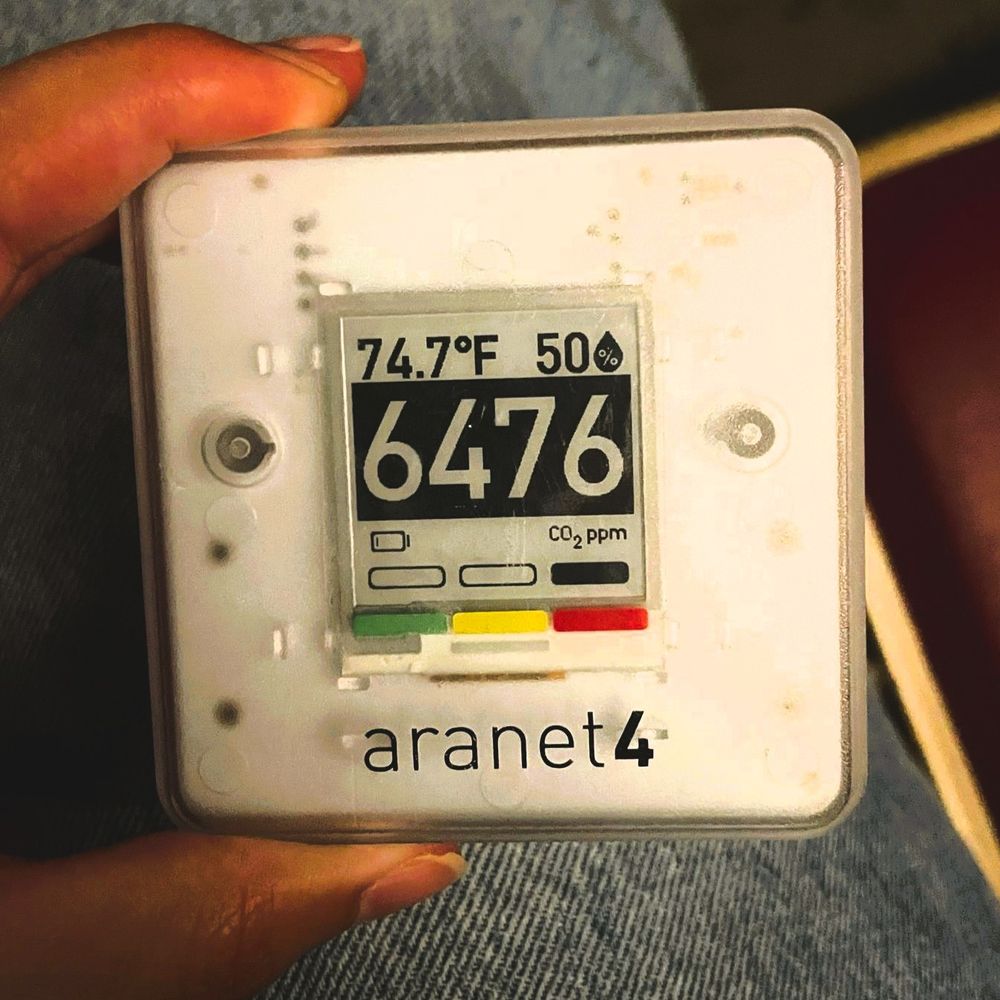 Fingers holding aranet monitor showing a reading of 6476ppm.
