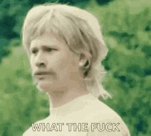 A GIF of a man with a moustache and mullet saying, “What the FUCK?!”
