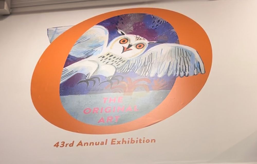 Sign for the Society of Illustrators 43rd Annual Original Art Show on a wall. Logo features an owl flying out of a large letter “O”. Text beneath reads “43rd Annual Exhibition”