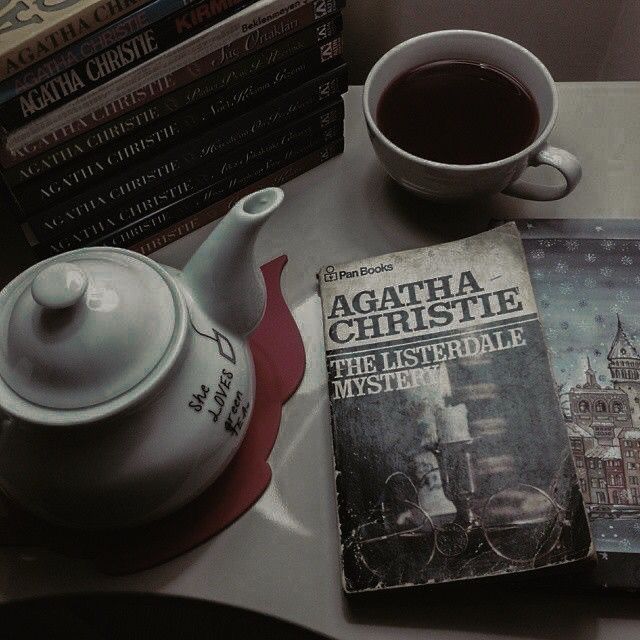 a pile of mystery books, a teapot and a tea cup as well as a copy of “the listerdale mystery” by agatha christie on a table 