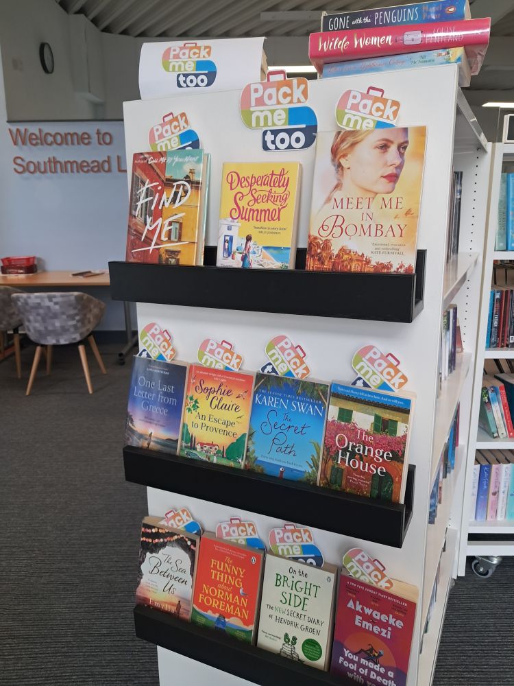 Holiday reads display in southmead library: a small bookshelf full of a wide variety of books and small bookmarks reading 'pack me too'