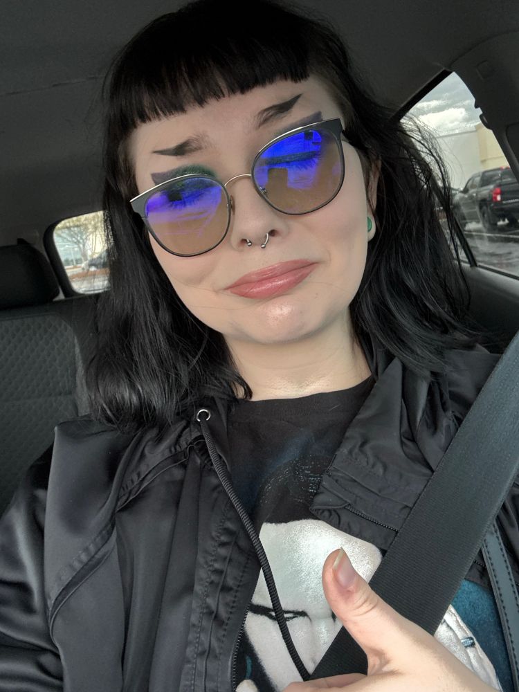 dumb alt bitch with half shaved eyebrows so she can draw them back on and she has a septum ring and thumbs upping the camera with a distraught face