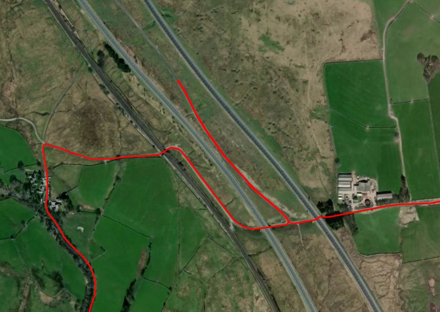 A satellite image with a GPS cycle track imposed in orange. The track can been seen going along a county lane, crossing a railway, going under one lane of a motorway, turning sharply to go parallel to the motorway before backtracking, turning sharply again and going under the other lane of the motorway.