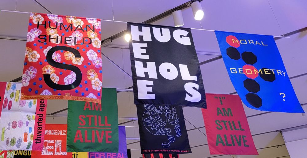 Banners that read, 'Human shield S', 'HUGE HOLES', AND 'Moral Geometry?'