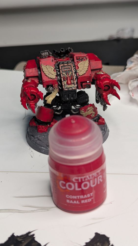 A blood angels furioso dreadnought menacing a bottle of red paint 