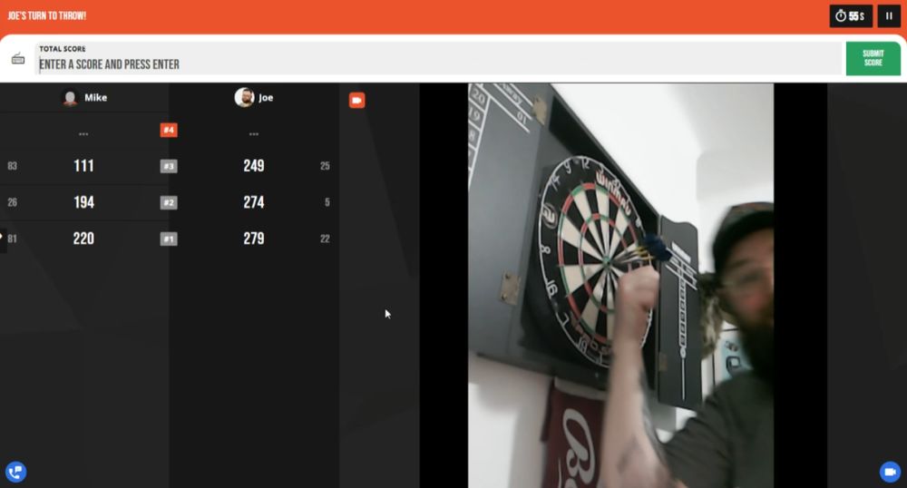 joe pointing at a fake triple bullseye to amuse his darts opponent 