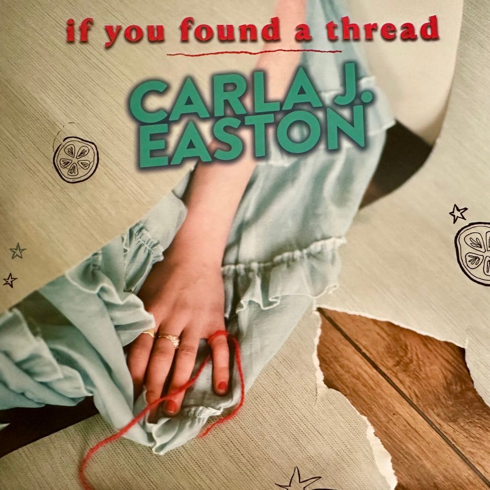 The image is the cover for Carla J Easton’s 7 inch single “If You Found A Thread” The image shows the title in red lowercase text with a red thread like line below it, and Carlas name in capitalised green lettering.  Carla’s forearm and hand emerging from ripped paper with prints of lemon slices and stars. Carla’s dress also emerges from between the paper with a small area of wooden floor also exposed. The hand is palm down, and a thick red embroidery thread tied to her pinky finger. The thread flows off of the bottom of the image as if connected to someone else. 
