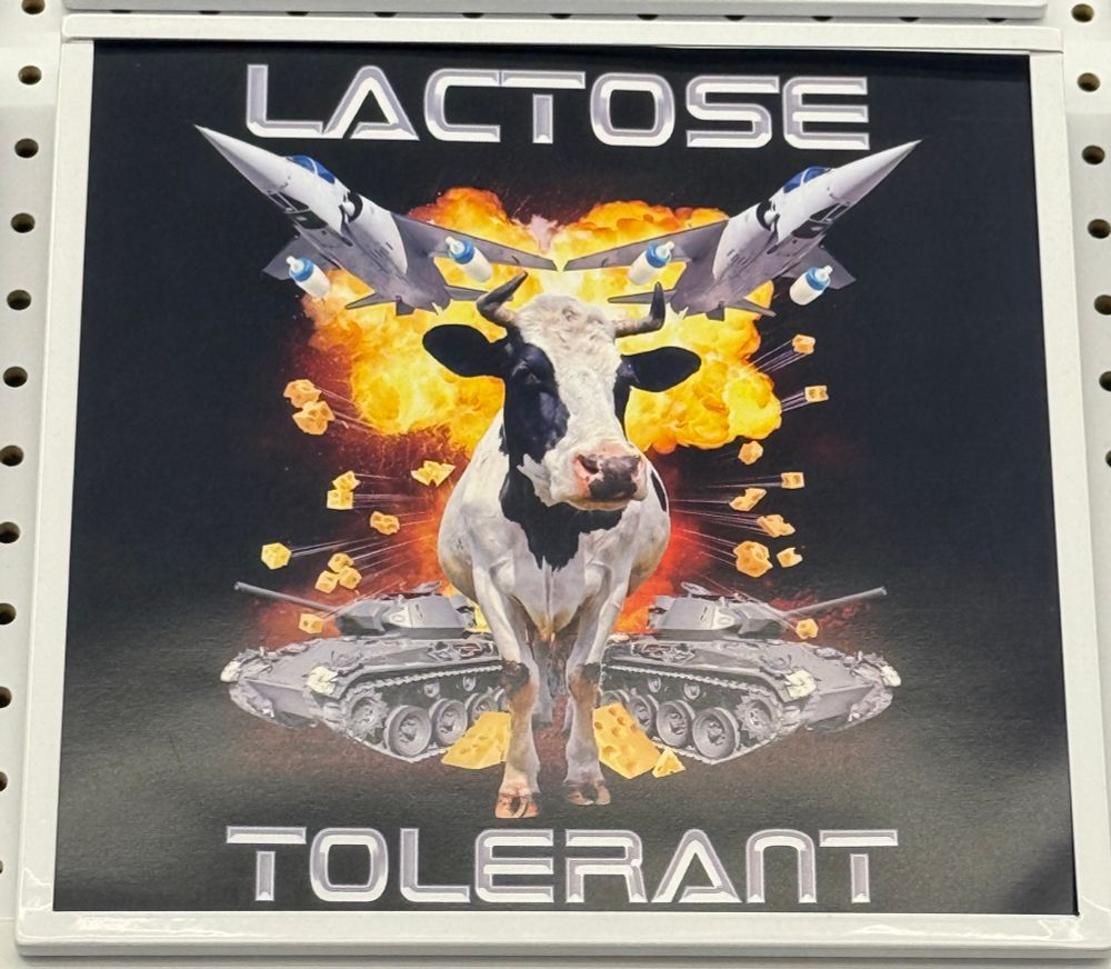 a black graphic t-shirt design with a cow, tanks, planes, an explosion, and text that reads “lactose tolerant”