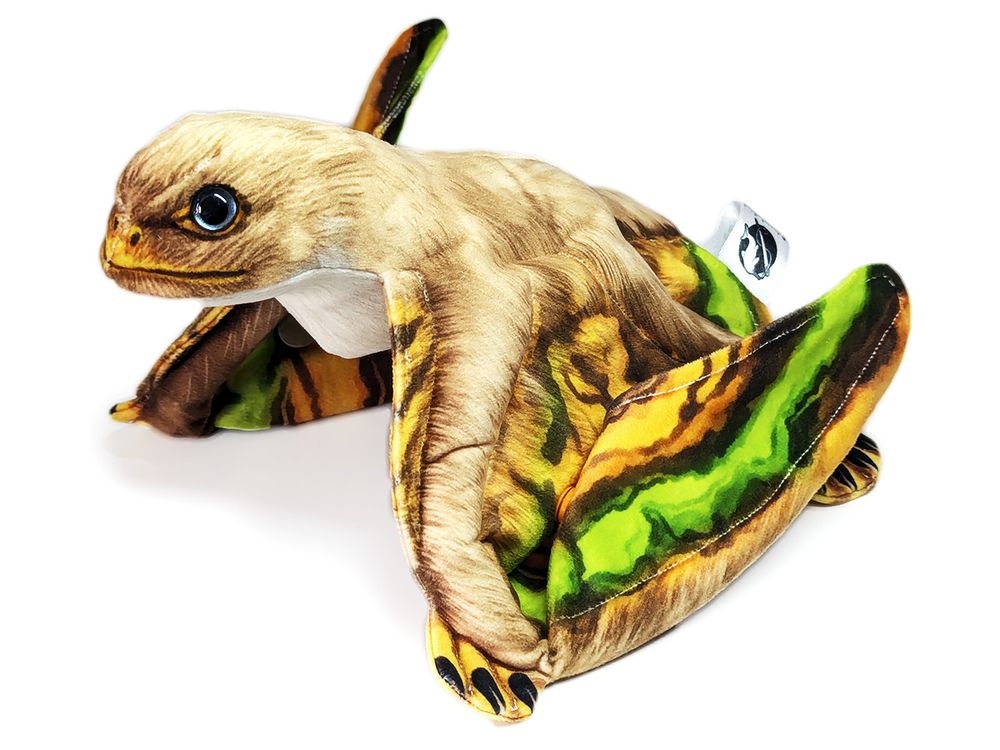 A realistic plush anurognathus- a species of small pterosaur. It has brown fur and striking green-orange wing membranes. Shiny dark eyes look soulfully at the camera.