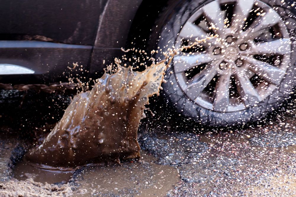 closeup of a car splashing dramatically through a large muddy puddle