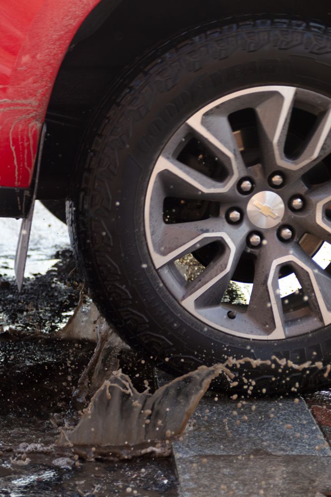closeup of a truck wheel splashing through a muddy puddle