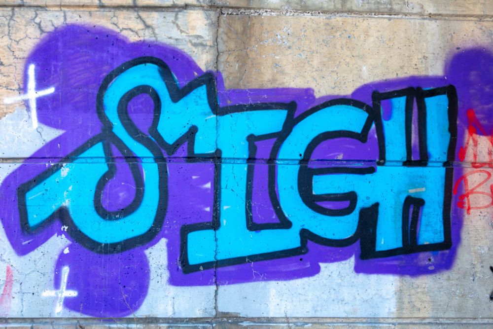 A bright blue and purple graffito reading "SIGH"