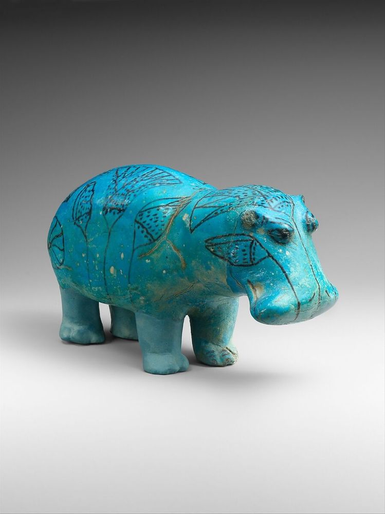 A middle Egyptian turquoise hippo from the met. He looks despondent and adorable. He has line art of reeds painted on his back and face. 