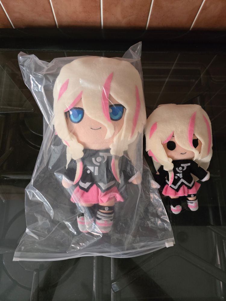 A photograph of the IA plushies by Akia-AP, one larger one with blue eyes in it's bag and one smaller one with round black eyes