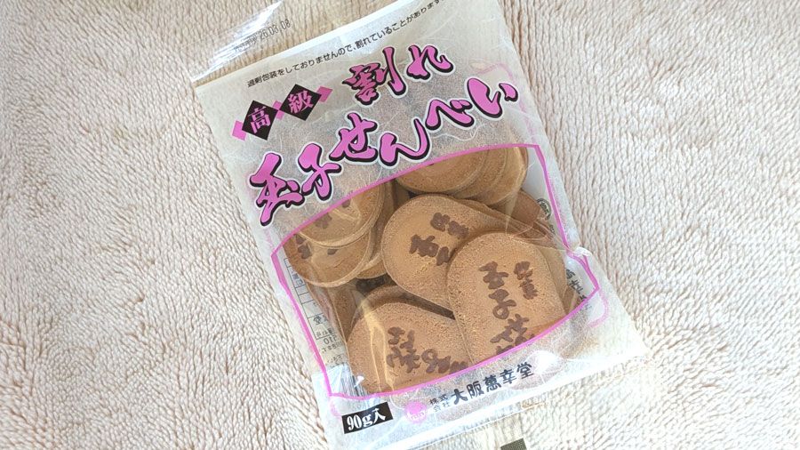 「高級割れ玉子せんべい」90g入りパッケージ表側。「銘菓玉子焼」の印が入った小判型の煎餅がパッケージの透明部分からたくさん見える。