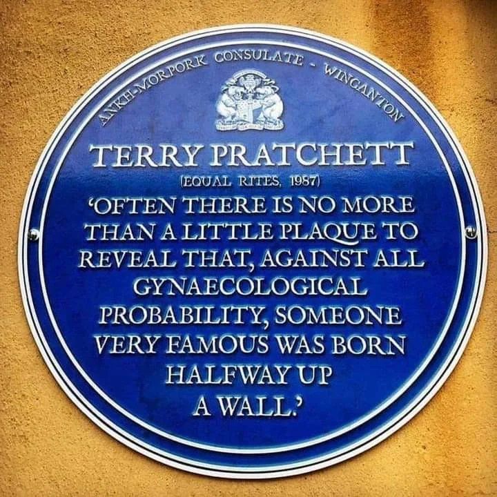 Circular, like a plaque half way up a building, on what could be a concrete wall background.

Curved writing at the top: ANKH-MOREPORK CONSULATE - WINGANTON

A family seal.

TERRY PRATCHETT
(EQUAL RITES, 1987)
'OFTTEN THERE IS NO MORE
THAN A LITTLE PLAQUE TO
REVEAL THAT, AGAINST ALL
GYNAECOLOGICAL
PROBABILITY, SOMEONE
VERY FAMOUS WAS BORN
HALFWAY UP
A WALL.'
