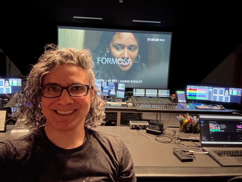 A photo of me sitting at a sound stage with a still from the short in the background. It shows a scared young woman