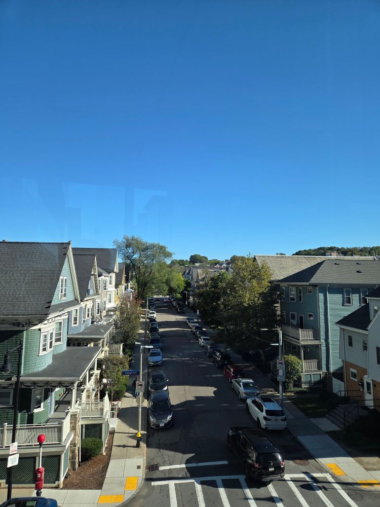 Overhead view of a neighborhood. The sky is clear and there is little traffic.