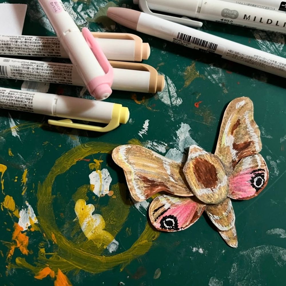 Work in progress shot of a paper moth and colouring pens 