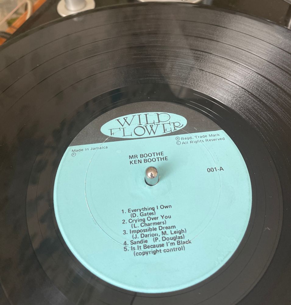 A powder blue record label with a logo saying ‘Wild Flower’, the LP title ‘Mr Boothe’ the artist’s name ‘Ken Boothe’ and the side A track listing on it, all in black type. 
It also says: Made in Jamaica