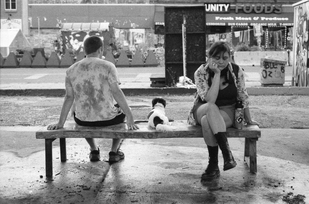 Two people and a dog rest on a bench. 