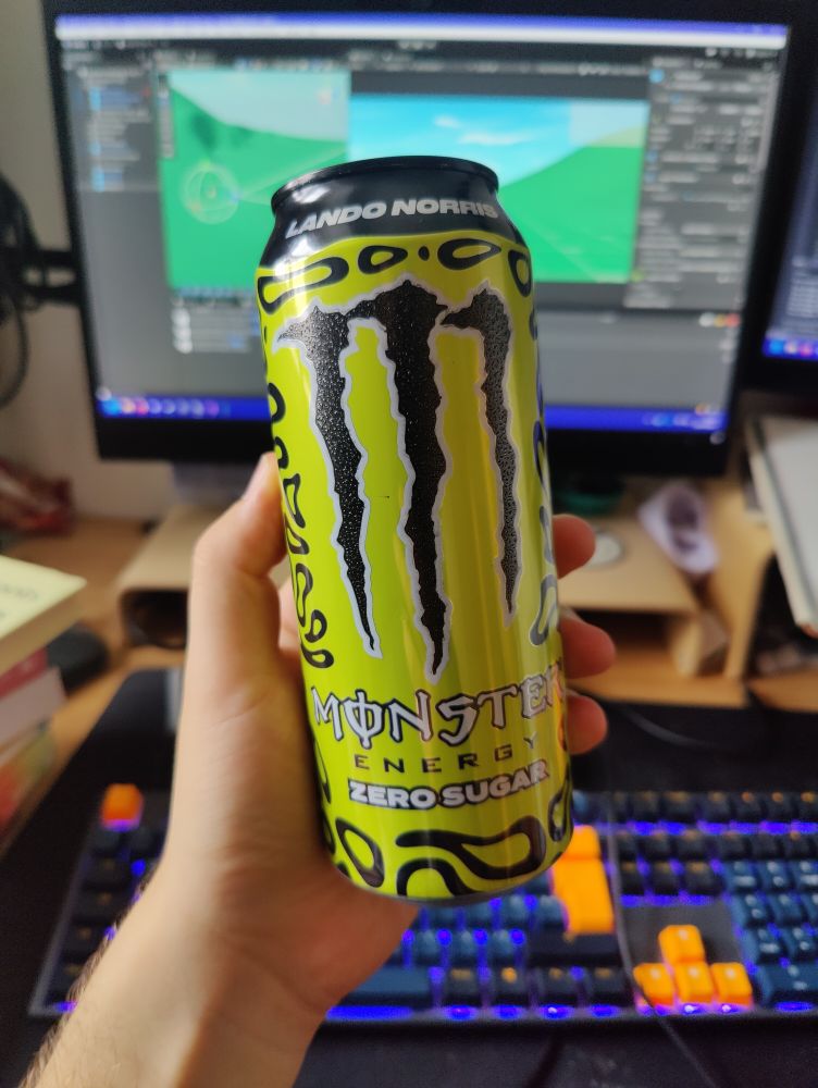 Luke holding a can of Lando Norris Special Edition Monster in front of a PC screen showing a Unity Game Scene.