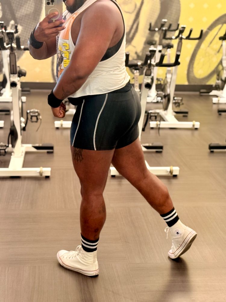 Picture of me with my back turned in the gym wearing a white crop top, black shorts, black socks and white shoes.