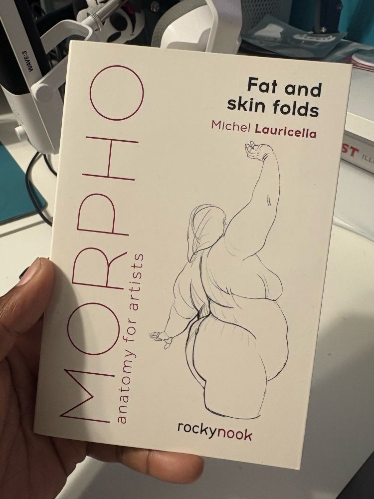 A picture of me holding the MORPHO Anatomy for Artists book about Fat and Skin Folds. 