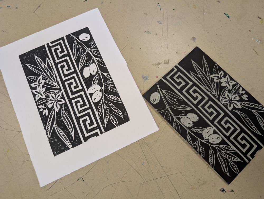 Print and lino showing a Greek key running down the center with an olive branch on one side and oleander on the other. Forgot to carve out one of the baby olives lol