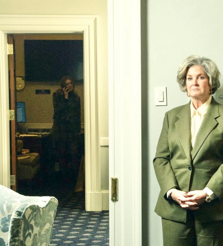 Brightened image reveals a woman on the phone in the darkened room across the hallway