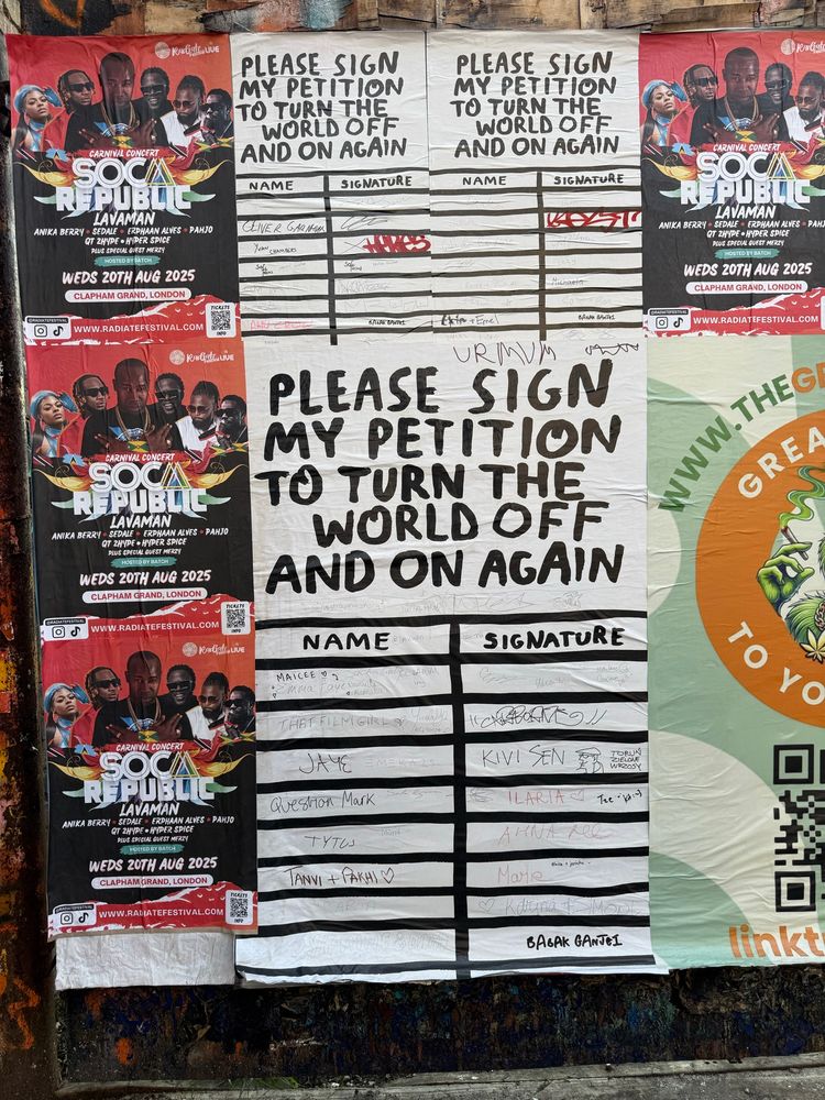 A wall covered in posters. In the middle of the picture is a large white poster with the words PLEASE SIGN MY PETITION TO TURN THE WORLD OFF AND ON AGAIN
written at the top, and a grid underneath with empty spaces for signatures. 

People have signed their names, including 
MAICEE " 5
THAT FILMGIRLS
JAYE
Question Mark
KIVI EN B
TYTOS
ANVI + PAKHI V
AHNA
Marie
