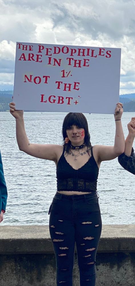 sign that says, "The pedophiles are in the 1% not the LGBT+" held by emo looking cutie