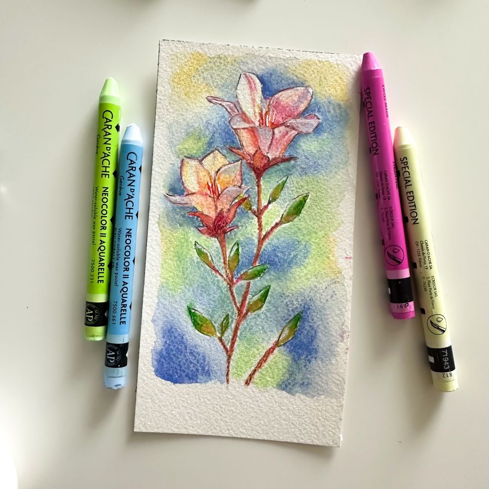 A watercolor illustration of flowers is displayed on textured paper, surrounded by four wax pastels in pastel colors: green, blue, pink, and yellow.