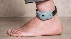 Photo du bas d'une jambe avec un bracelet électronique au pied.