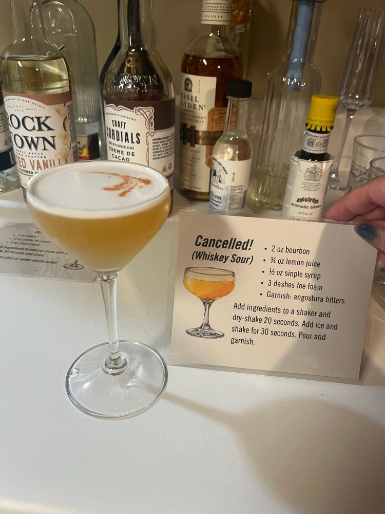 A whiskey sour next to the recipe card
