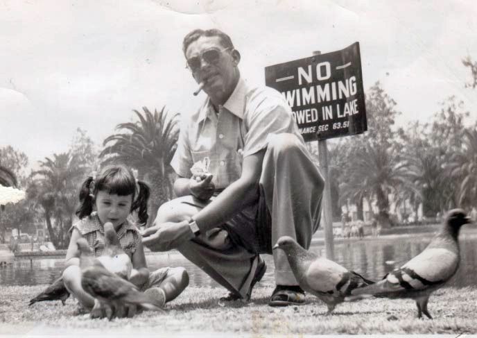 This is a black-and-white photo of me at about 3 years old, feeding pigeons in MacArthur Park, Los Angeles, with my dad* in 1953. Named for General Douglas MacArthur after the war, it was called Westlake Park before the war.  

There is a sign behind us that says "No Swimming Allowed in Lake." This is how I remember MacArthur Park.
