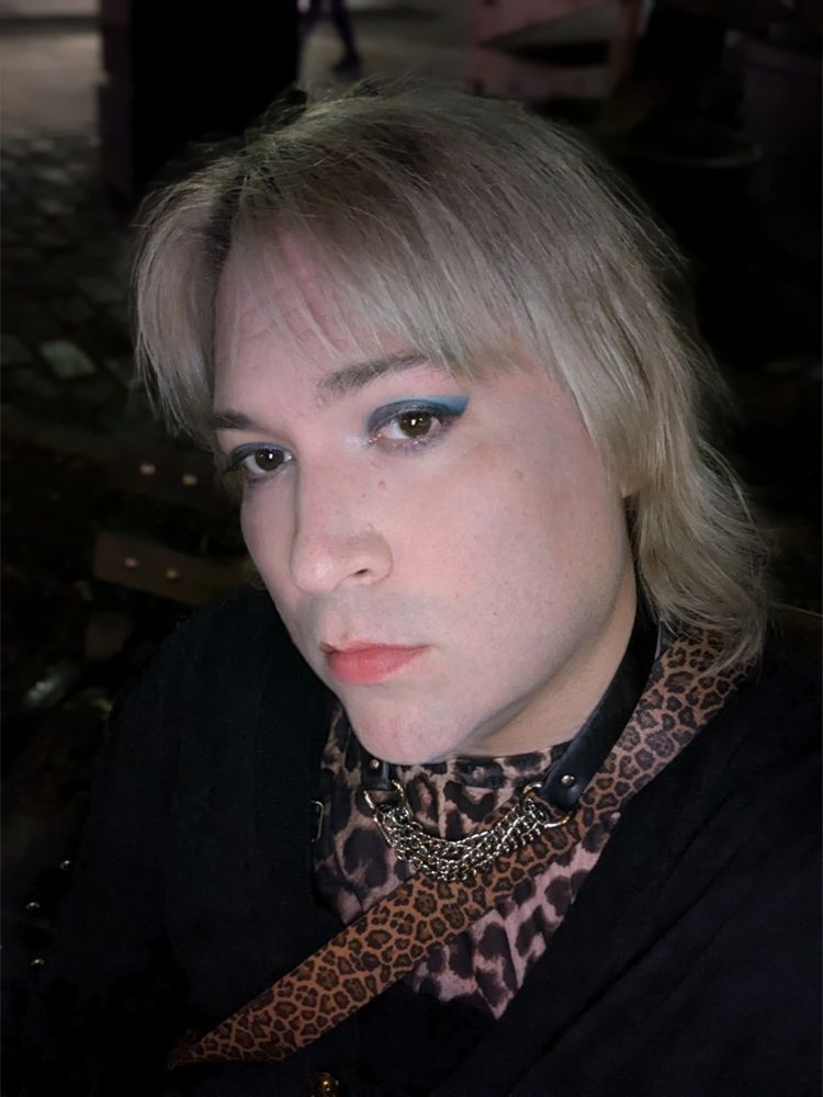 Blonde with blue eyeshadow and a leopard top under a black cardigan. 