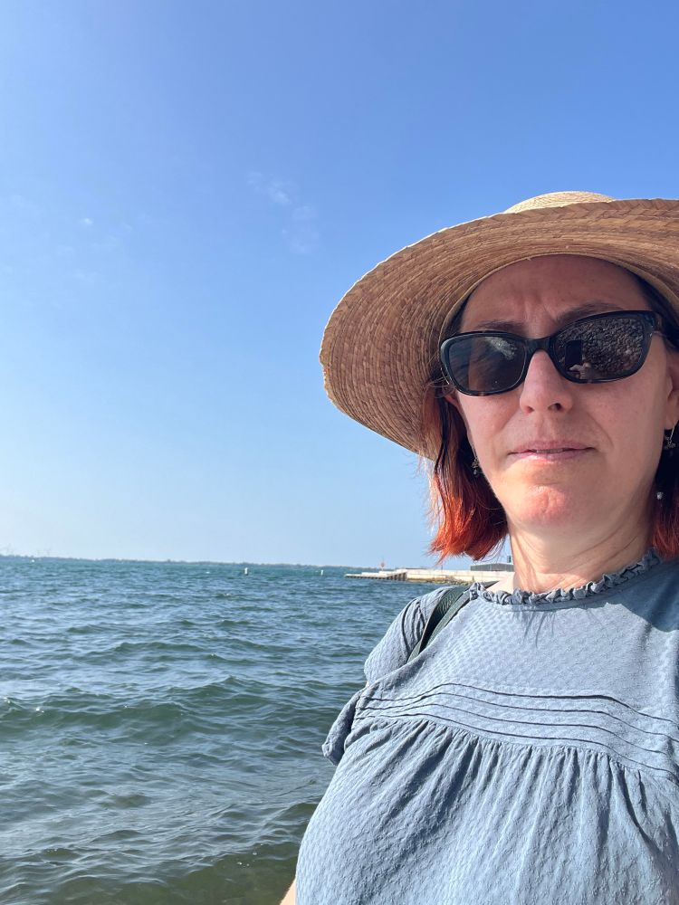 A woman in a sunglasses and sunhat in Lake Ontario 